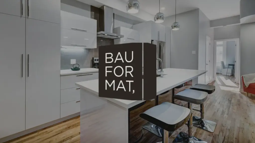 Modern kitchen with white cabinets, island with barstools, pendant lights, and wood flooring. The logo BAUFORMAT is centered and partially blocking the view of the kitchen.