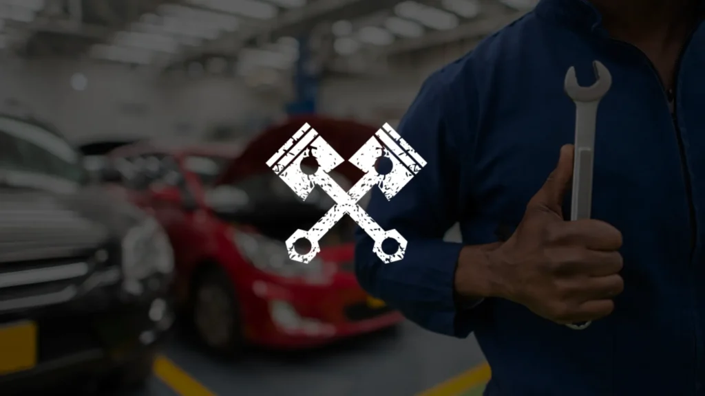 A mechanic in a blue uniform holds a wrench in front of his chest, standing in an auto repair shop with cars in the background. A white graphic of crossed pistons overlays the center of the image.